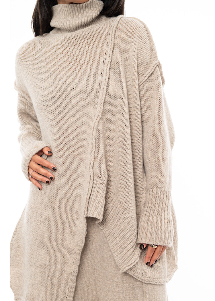 An up close off A Model wearing a creme Knitted Pullover.Showing the seam-lines in more detail and the materials definition.