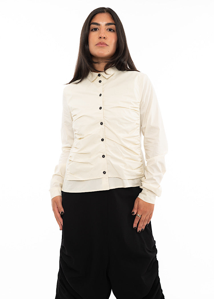 A Model wearing a fitted ruched buttoned up Shirt, paired with a pair of black trousers.