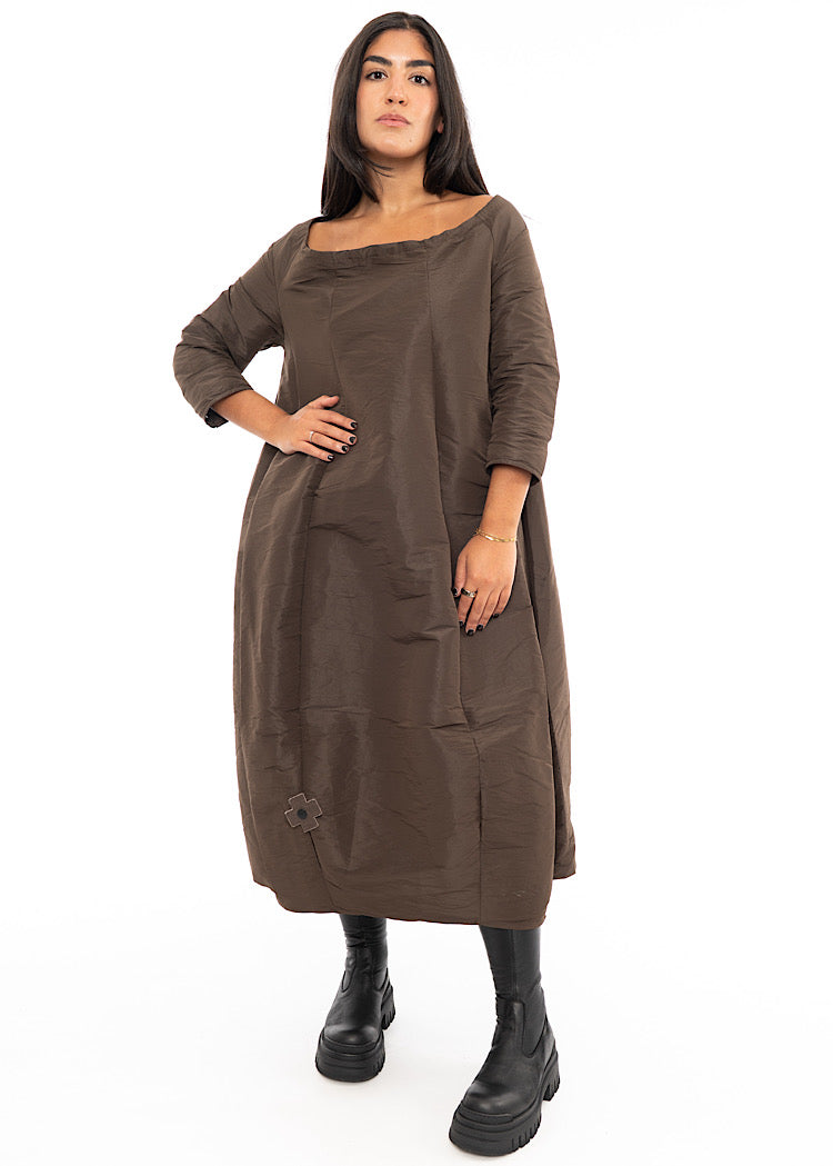 A Model wearing a structured balloon styled dress. Featuring a slash neckline, three-quarter length sleeves and side seam pockets.Styled with Black Boots