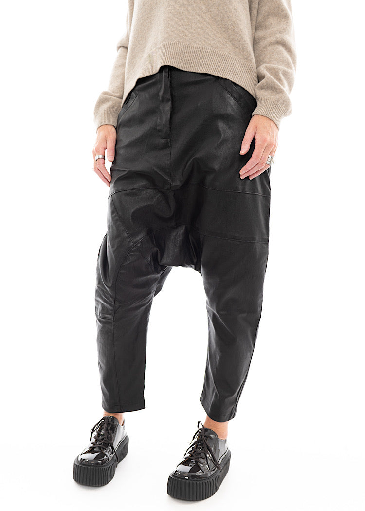 A Model wearing a Structured Drop-Crotch Black Leather Trouser, disclosing the slight rucking effect on the knee.