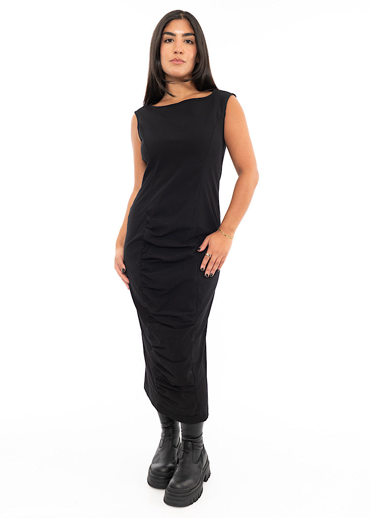 A Model wearing a fitted, sleeveless dip neck-line Dress in a Black colour. Styled With Black Chunky soled Boots.