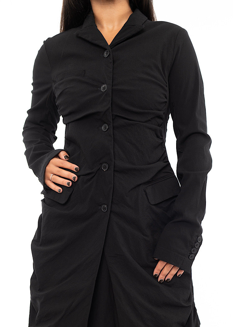 An up close off A Model wearing a detailed techno coat and matching trousers, in a Black colour. Showing the fitted look and buttons in more detail.