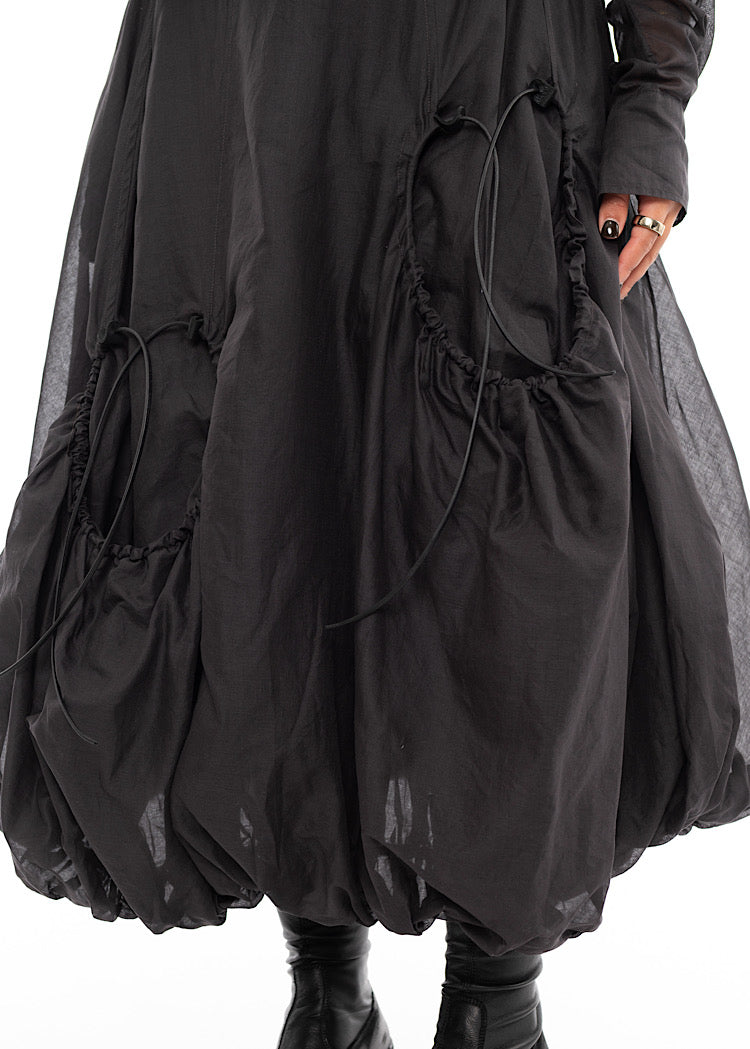 An up close photo of A Model wearing a bubble skirt, in a Grey colour. Focusing on the Black string details in more depth.