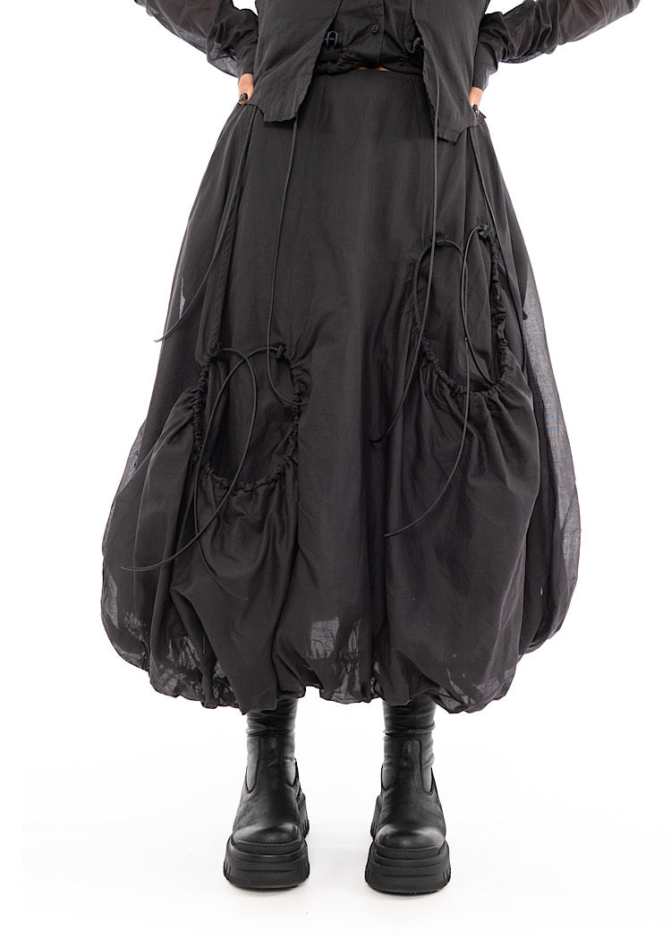 An up close photo of A Model wearing a bubble skirt, in a washed Grey colour. Focusing on the Black drawstring details and pockets.