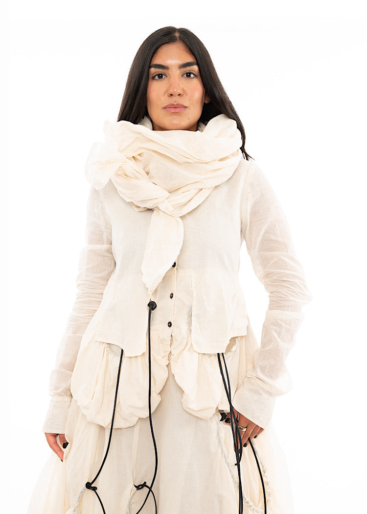A Model wearing a papered material Scarf, paired with a matching Jacket and Skirt.