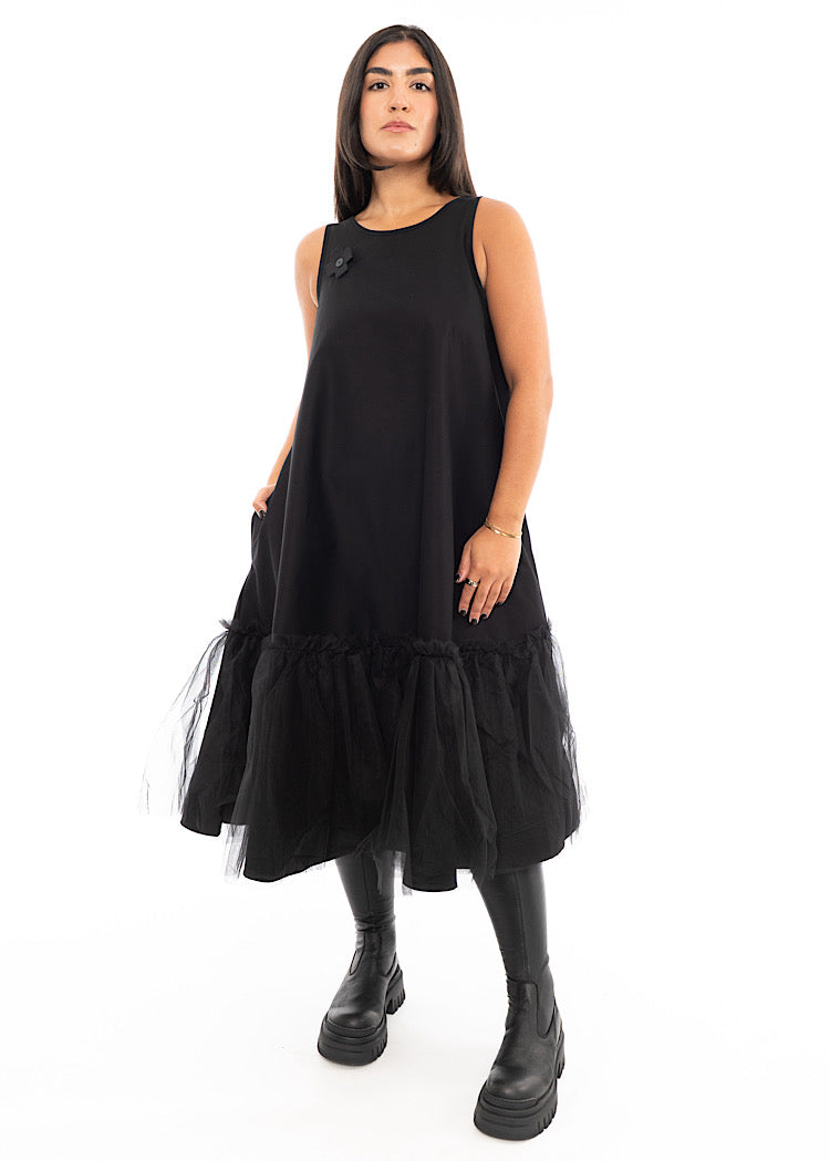 A Model wearing a fitted Black dress which bottom hem turns into a floaty mesh skirt. Styled With Black Chunky Boot.