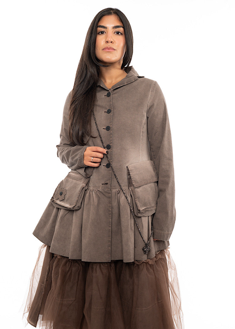 A Model wearing a long beaded necklace with a cross pendent styled with a washed Chocolate Brown Jacket and a Chocolate mesh dress.