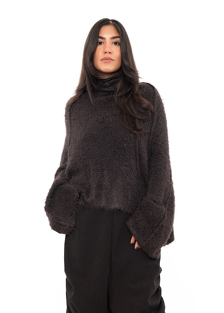 A Model wearing a Chocolate Fluffy pullover featuring a relaxed turtle neck feature and an oversized fit. Paired with matching trousers.