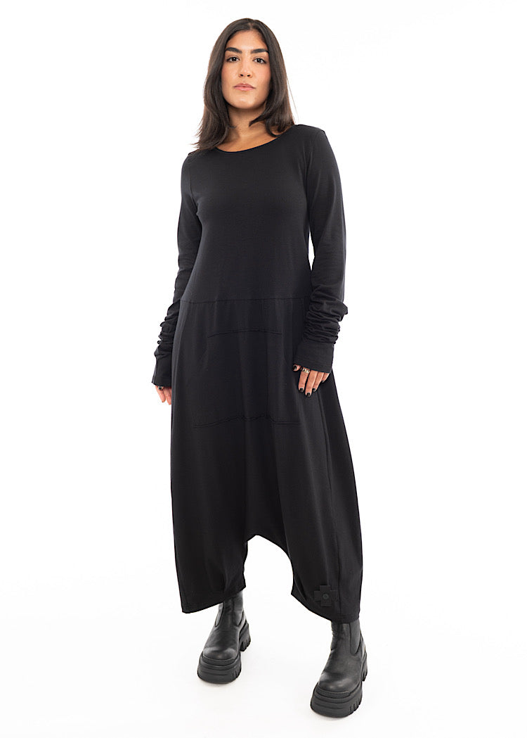A Model wearing a slouchy oversized Black Jumpsuit, with rouged up sleeves and an exaggerated drop crotch. Styled with a Black Chunky Boot.