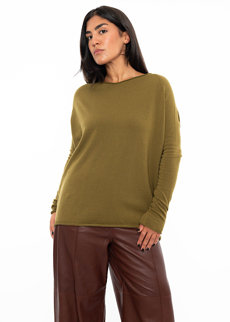 A Model wearing a relaxed fit khaki green pullover with a slash neckline and long sleeves. Styled with burgundy wide leg leather trousers.