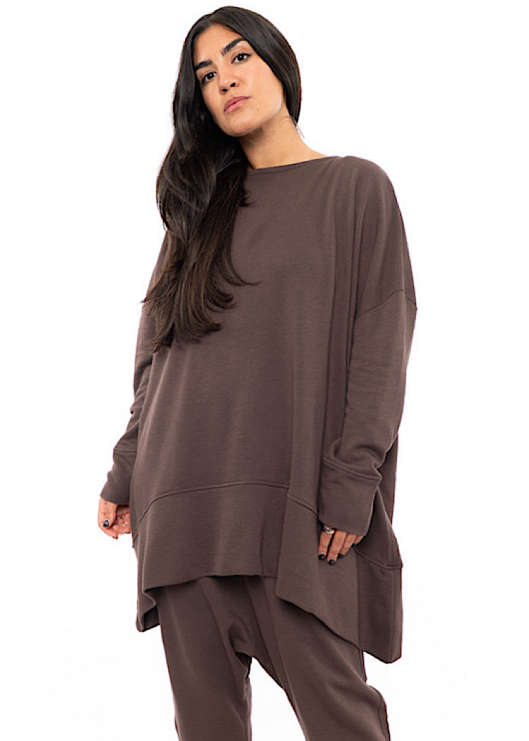 A Model wearing an oversized Plum toned Pullover, paired with a Matching Trouser.