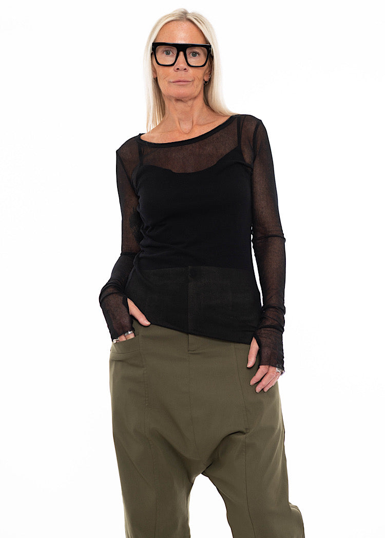 Model wearing black sheer mesh long-sleeve top with fitted camisole and olive green drop-crotch trousers – modern layered outfit for AW25 womenswear collection.