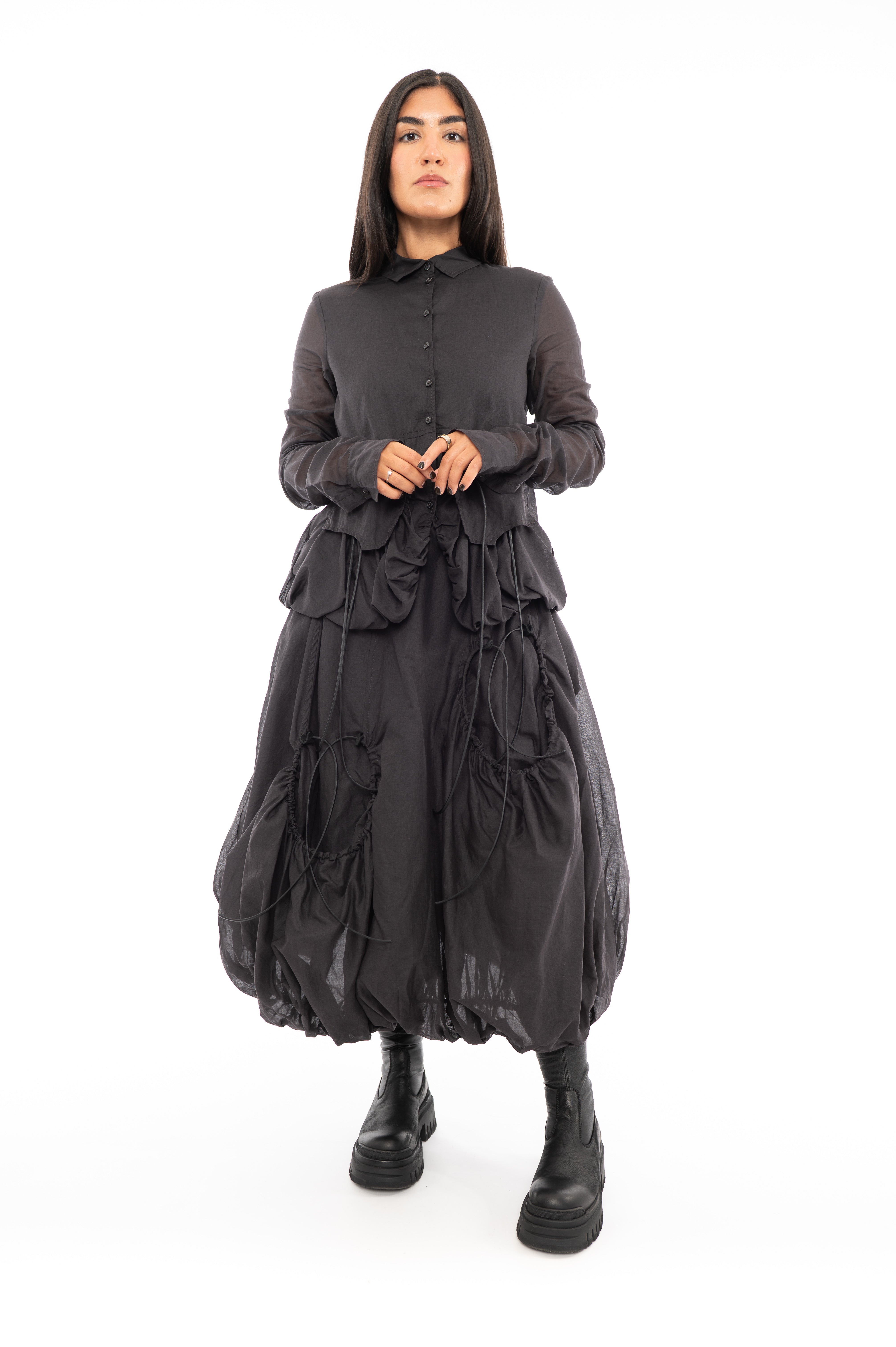 A full frame photo of A Model wearing a bubble skirt and Jacket, in a matching washed Grey colour. Focusing on the Black string details.