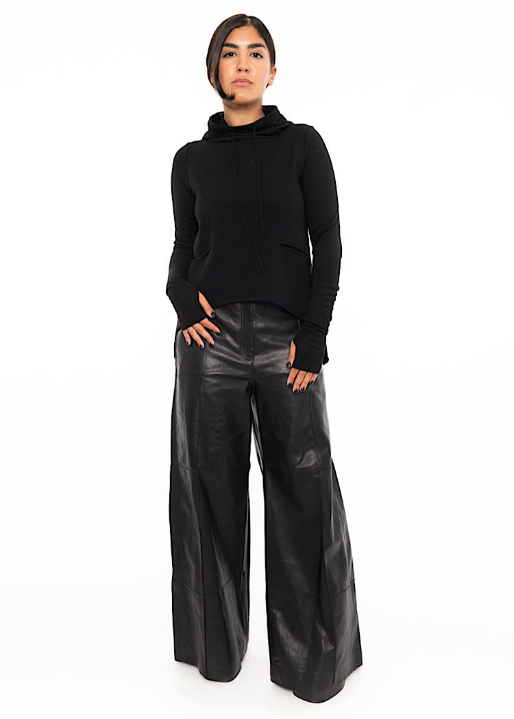 A model wearing straight leg leather trousers styled with a black fitted pullover with long sleeves. Showing a concealed zipper to fasten.