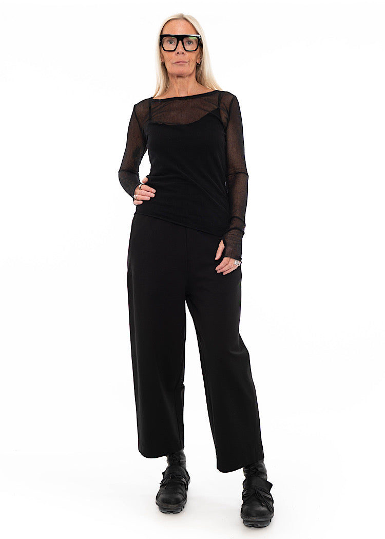 Model wearing a straight leg black trouser with side pockets, styled with black mesh top and black utilitarian boots.