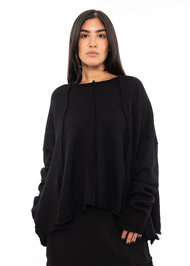 A Model wearing a Black Pullover, featuring distinct seam-lines throughout the piece. Paired with a Black Trouser.