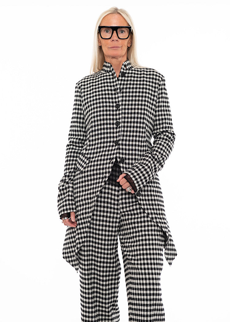 Model wearing a black and white gingham check longline shirt with asymmetric hem, paired with matching wide-leg trousers.