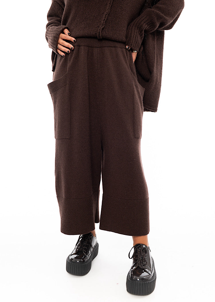 A Model wearing a Brown Knitted Skirt with pockets. Paired with a matching coloured Pullover and Brown patent shoes.