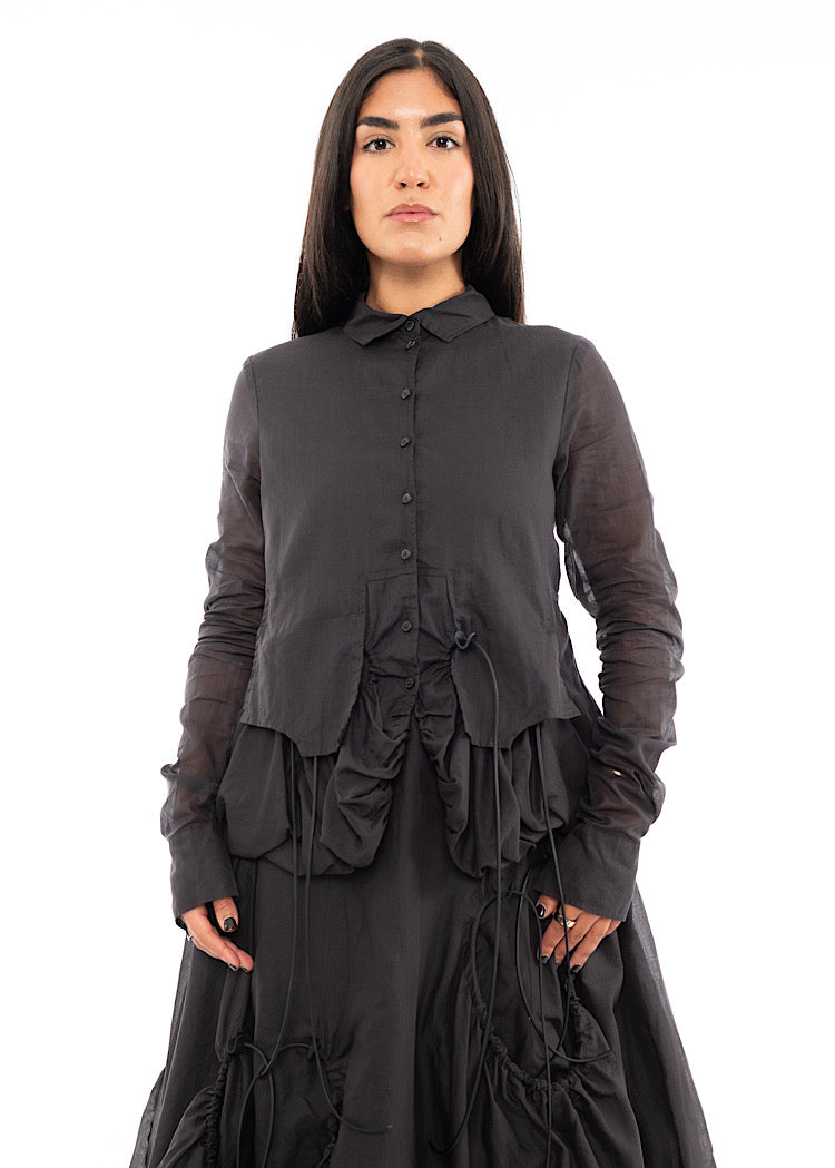 A Model wearing a sculptural Jacket with a matching Skirt in the same washed Grey colour.