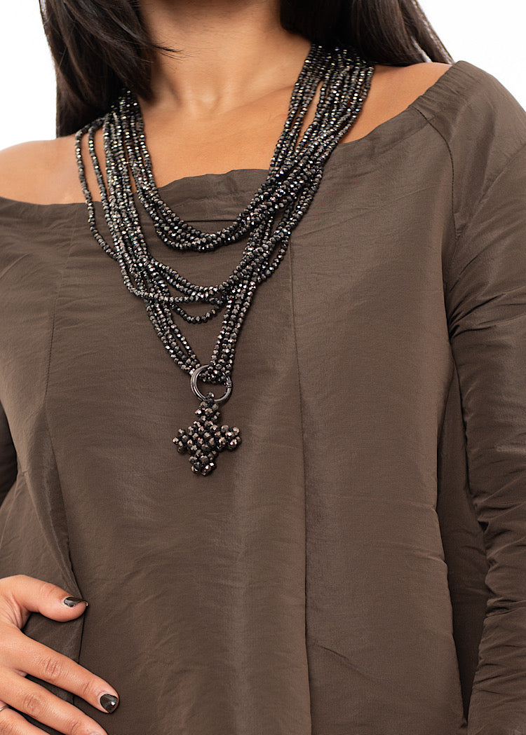 A Model wearing a triple layered circular beaded chain with a pendent and clasps too close.Styled with a Chocolate Brown dress.
