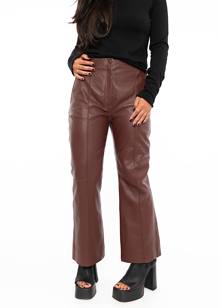 Model wearing cropped, flared Burgundy leather trouser with a black fitted pullover. A seam detail down the centre of the leg.Styled with Black high heels.