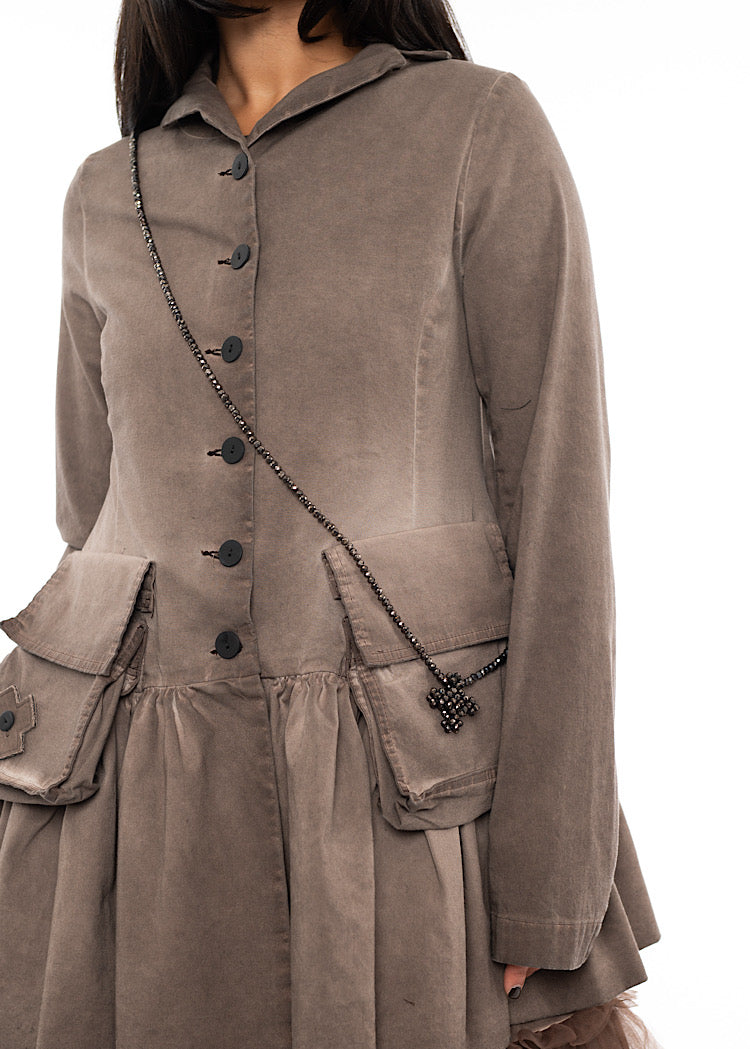 An up close off A Model wearing a chunky long across the body Necklace. Showing the circular beads in more detail.