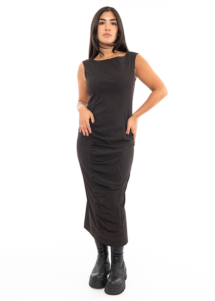 A Model wearing a fitted, sleeveless Dress in a washed dark Brown colour. Styled With Black Chunky soled Boots.