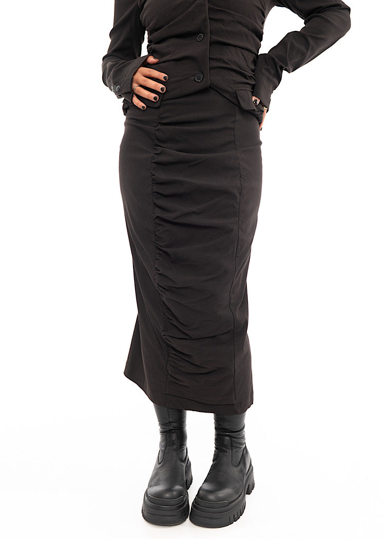 A Model wearing a fitted washed Brown Skirt, paired with a matching Jacket and Black Chunky soled Boots.