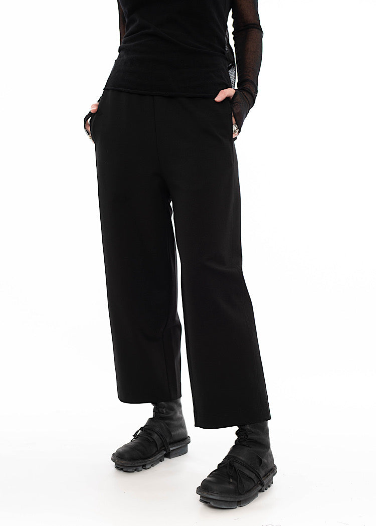 Model wearing a straight leg black trouser with side pockets, styled with black mesh top and black utilitarian boots.