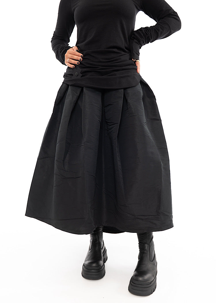 A Model wearing a Black Structured Skirt, paired with a long sleeved stretch top and Black Chunky Boots. Focusing on the size/shape of skirt.