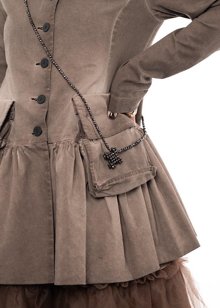 An up close off A Model wearing a chunky long across the body Necklace. Showing the cross pendants circular beads in more detail.