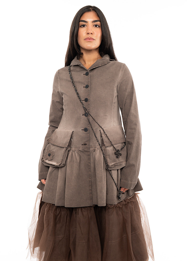 A Model wearing a long beaded necklace with a cross pendent styled with a washed Chocolate Brown Jacket and a Chocolate mesh dress.