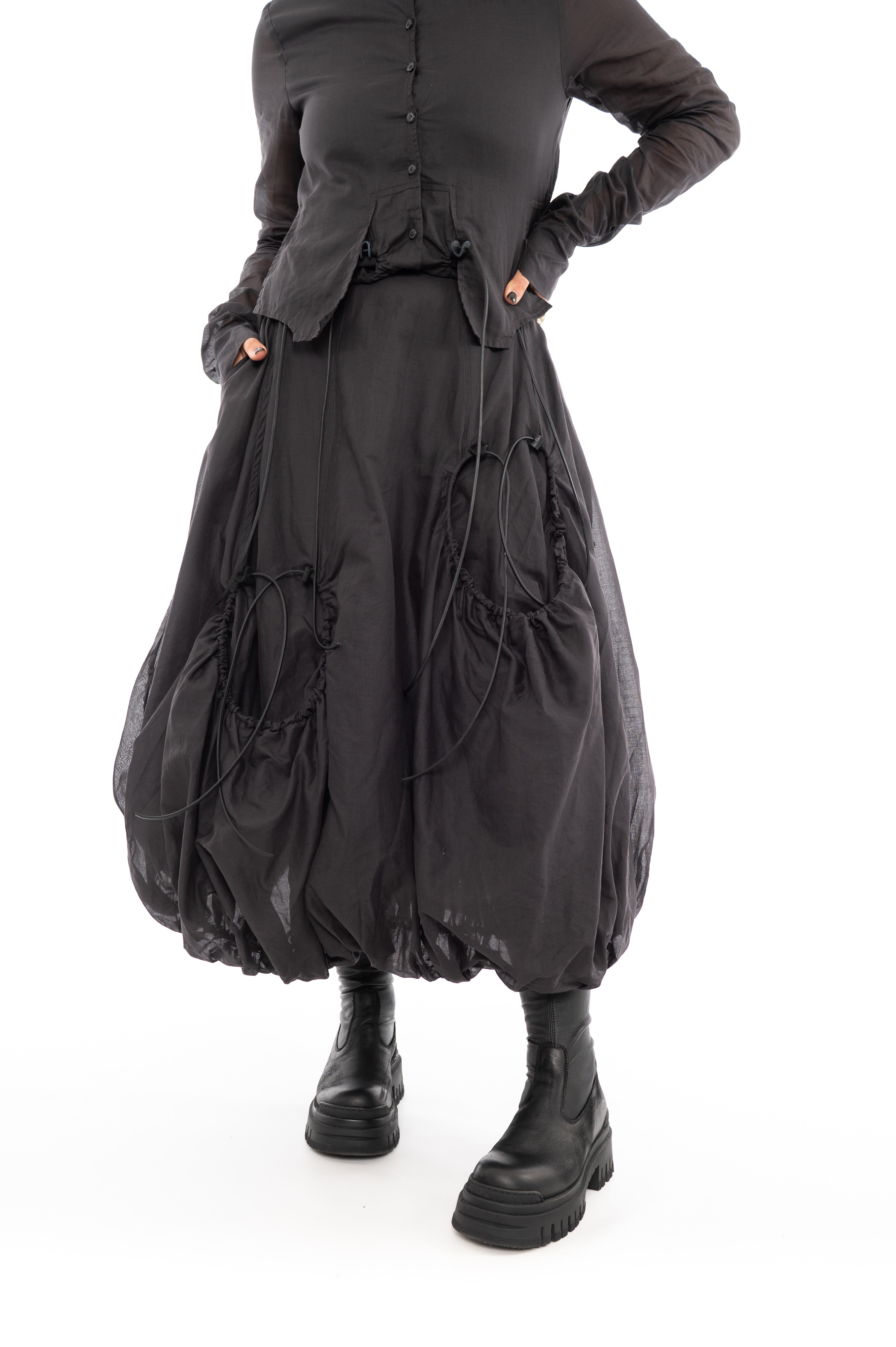 An up close photo of A Model wearing a bubble skirt, in a washed Grey colour. Focusing on the Black string details and distinct pockets.