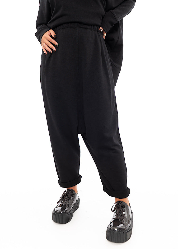 A Model wearing a Black fitted Trouser with a semi rolled up ankle. Paired with a Brown Patent Shoe.