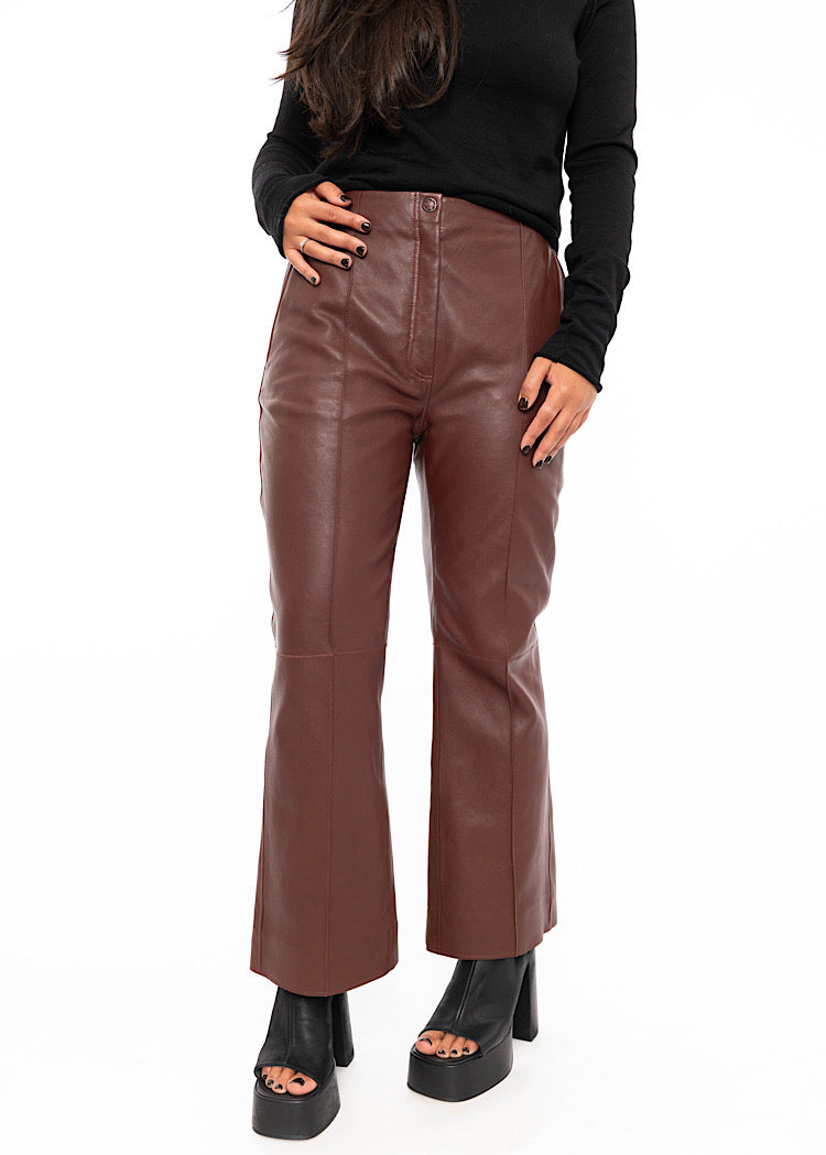 Model wearing cropped, flared Burgundy leather trousers with a black fitted pullover. Styled with Black high heels.
