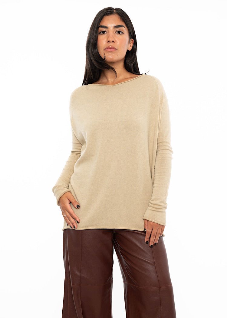 A Model wearing relaxed fit beige pullover with a slash neckline and long sleeves. Styled with burgundy wide leg leather trousers.
