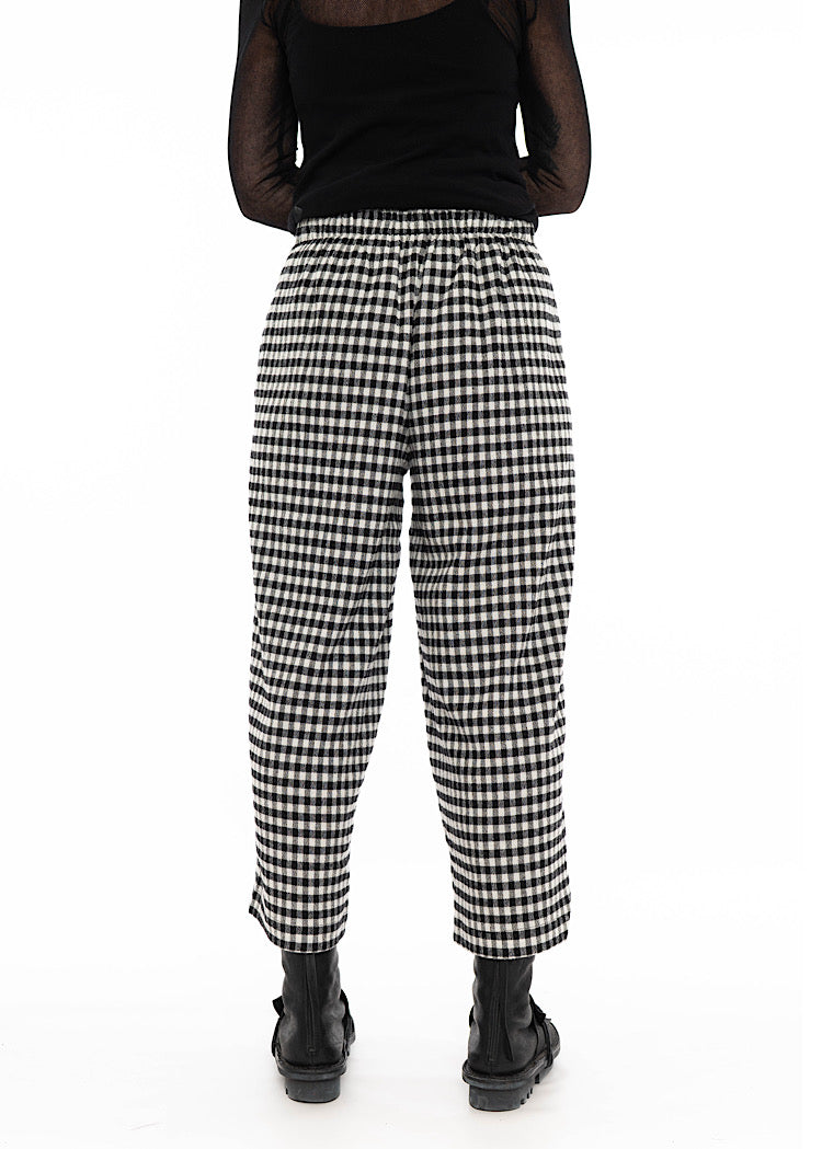 Rear view of model wearing black and white gingham check wide-leg trousers with side pockets, cropped ankle length, styled with black top and black combat boots