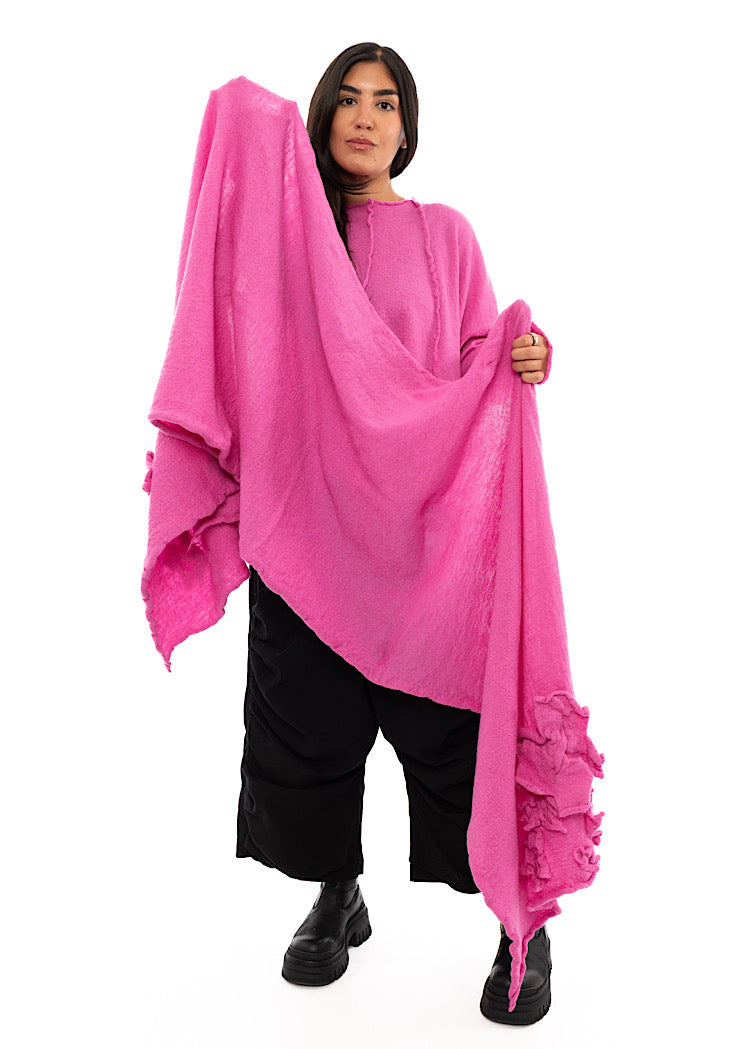 A full frame photo of A Model holding up a Bright Pink Scarf with ruffled details surrounding the bottom of the piece.