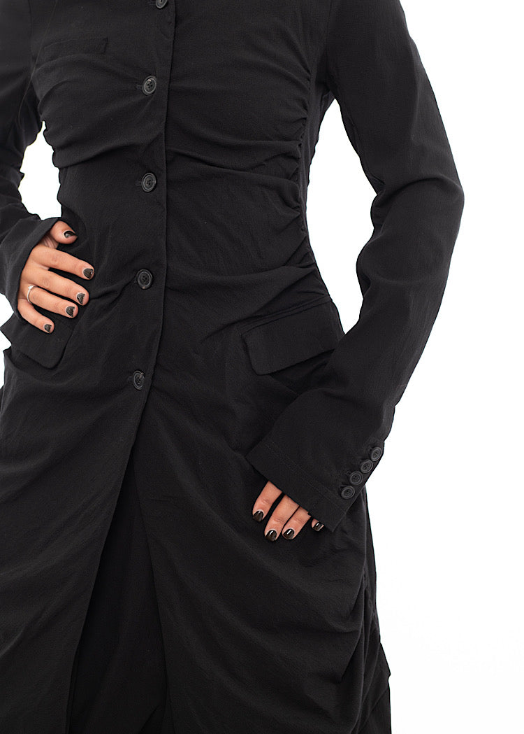 An up close off A Model wearing a detailed techno coat and matching trousers, in a Black colour. Showing the fitted look and buttons in more detail.