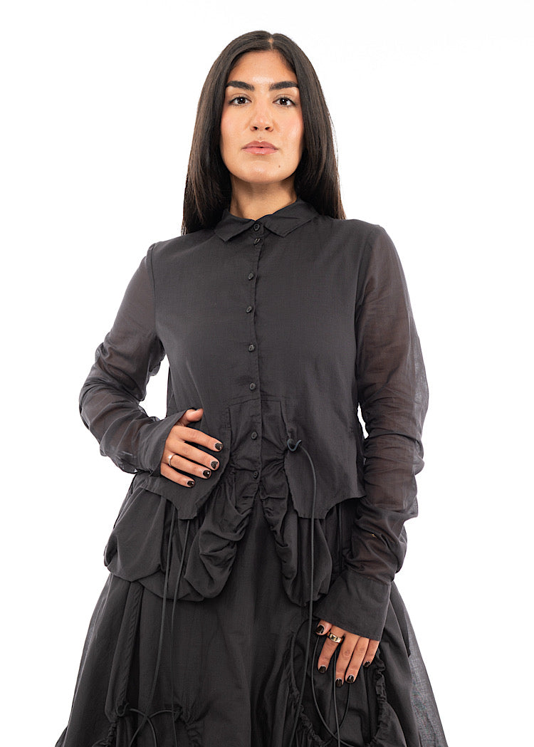 A Model wearing a sculptural Jacket with a matching Skirt in the same washed Grey colour.