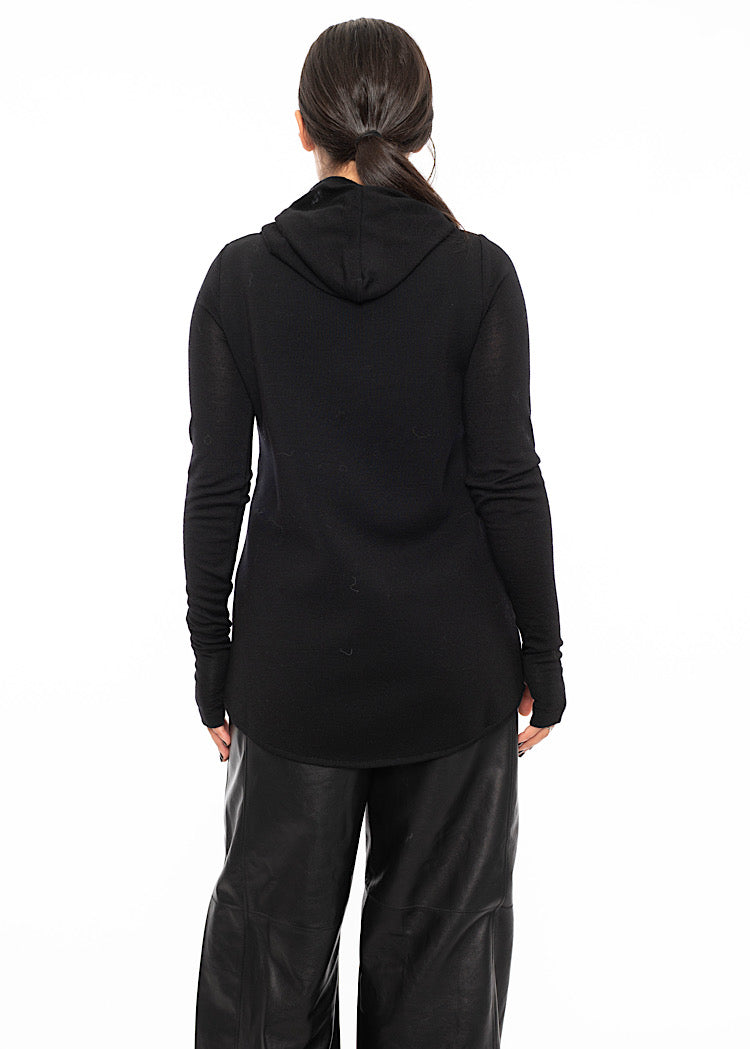 A model wearing a fitted black pullover standing facing the back, showing the hooded detail and the slight ruffled effect on sleeves.