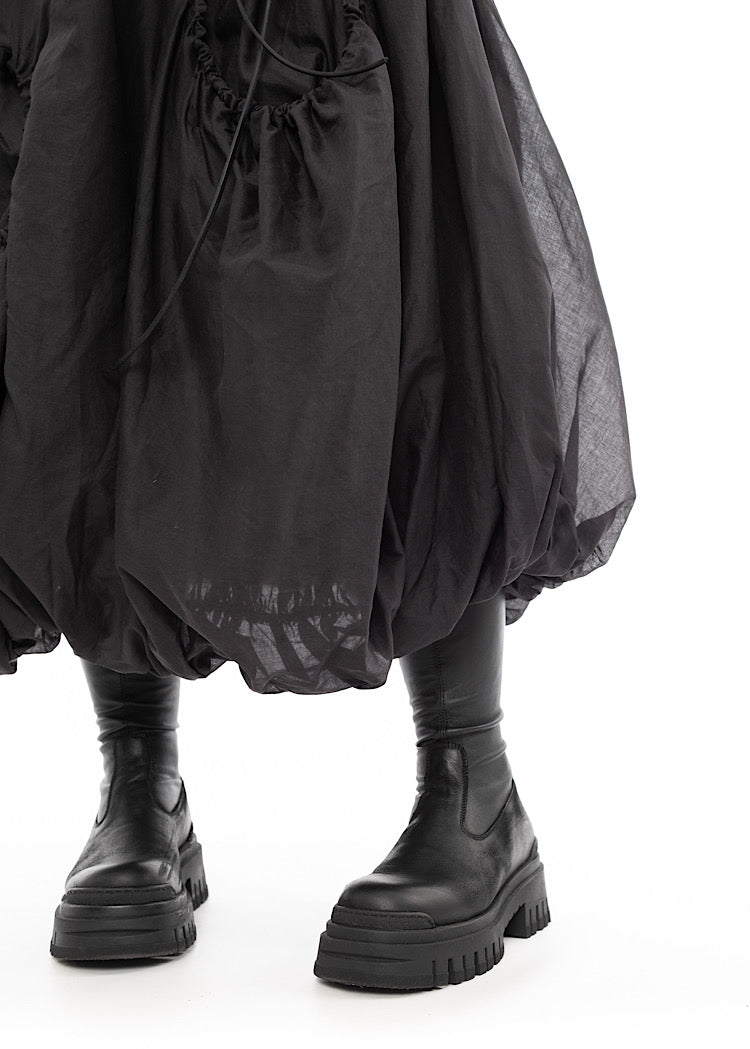 An up close photo of A Model wearing a bubble skirt, in a Grey colour. Focusing on the quilted hem in more detail.