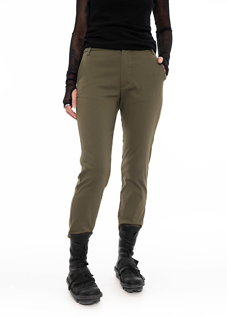 Model wearing slim-fit olive green trousers with a tapered leg, flat front, and side pockets, styled with a black mesh long sleeve top and black utility boots.