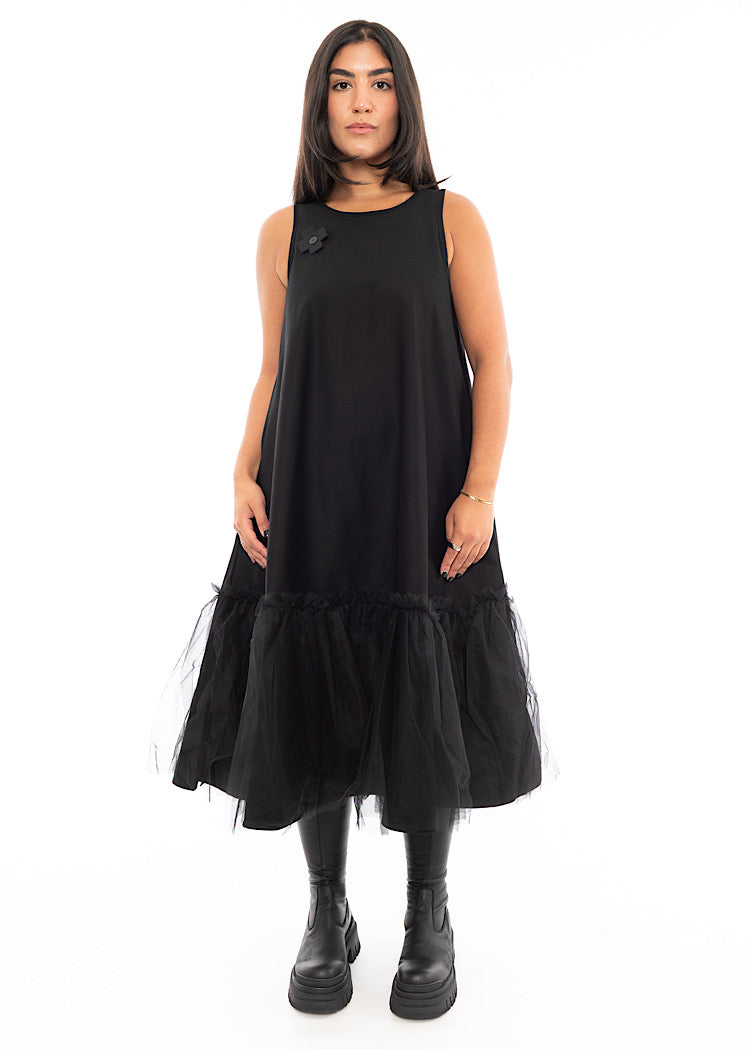 A Model wearing a fitted Black dress which bottom hem turns into a floaty mesh skirt. Styled With Black Chunky Boot.