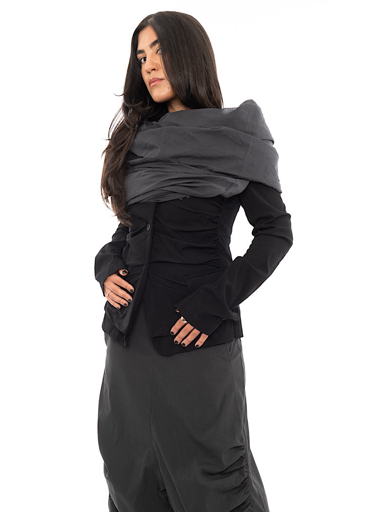 A Model wearing an oversized Scarf in a Washed Grey colour, styled with a Black Jacket and a Washed Grey trouser.