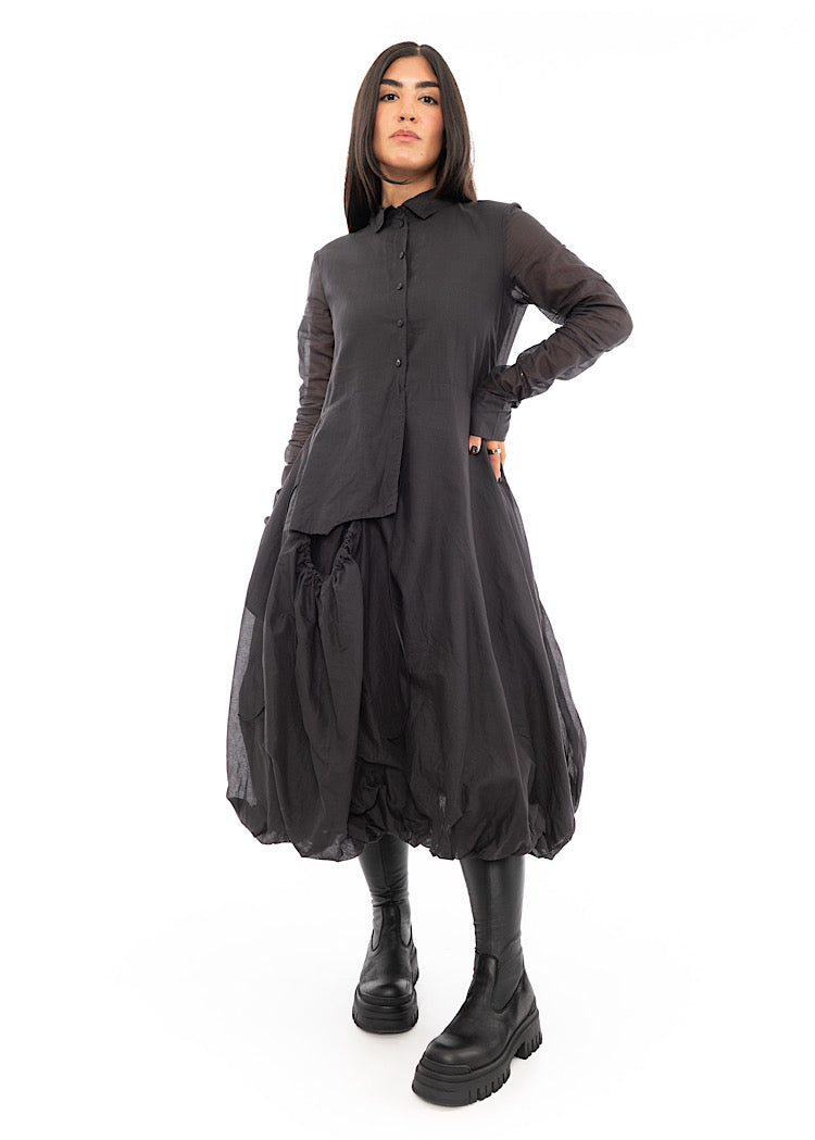A full frame photo of A Model wearing a bubble skirted Dress in a washed Grey colour. Focusing on the flap pocket, paired with a Black Boot.