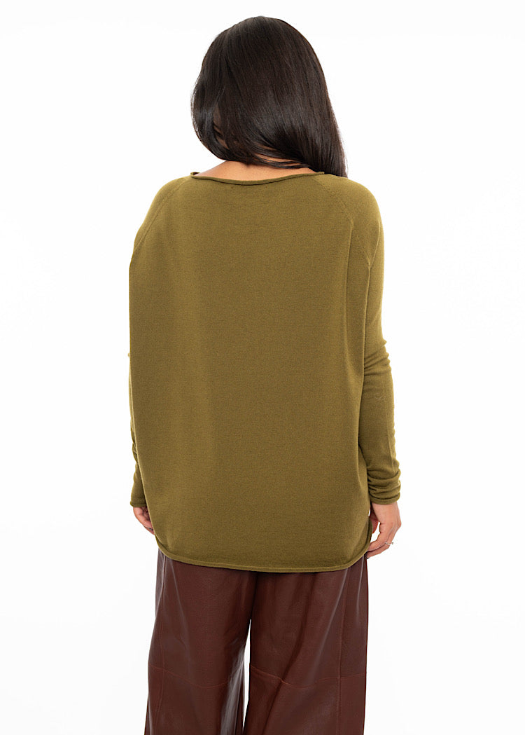 A Model standing facing the back wearing a relaxed fit khaki green pullover with a slash neckline and long sleeves. Showing the back length of the piece.