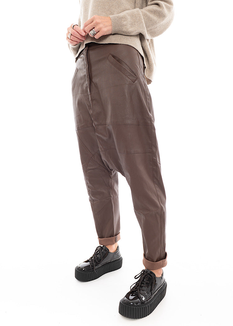 A Model wearing a Structured Drop-Crotch Brown Leather Trouser. Showing the two front Pockets on a slant.