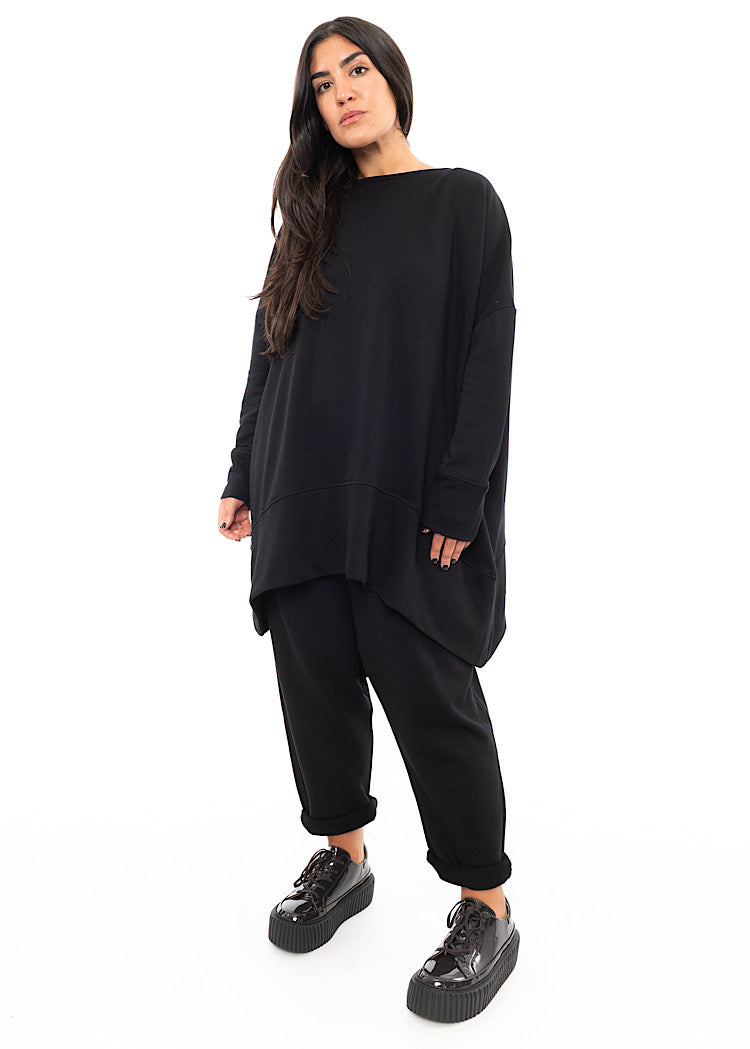 A Full frame photo of A Model wearing a Black Oversized Pullover. Showing the oversized but straight fit of the piece.