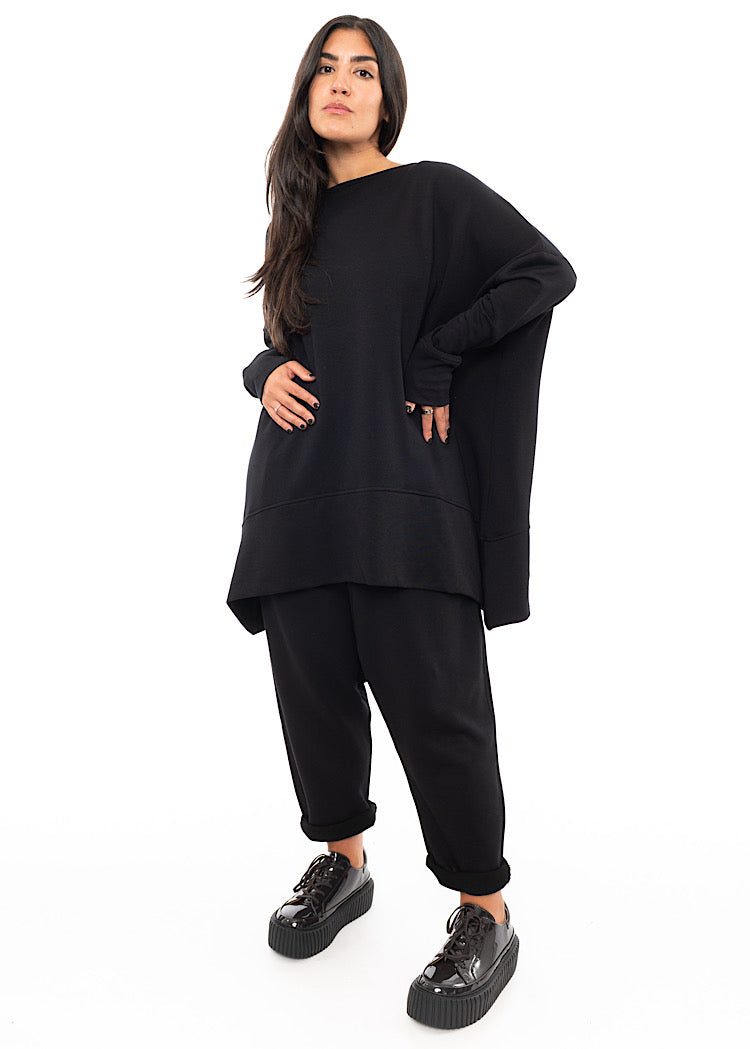 A Full frame photo of A Model wearing a Black Oversized Pullover. Showing the oversized but straight fit of the piece.